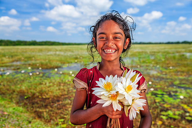 Home sri lankan little girl with lotus flowers in a lake near sigiriya, ceylon.